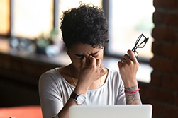 Young woman pinching between her eyes in pain.
