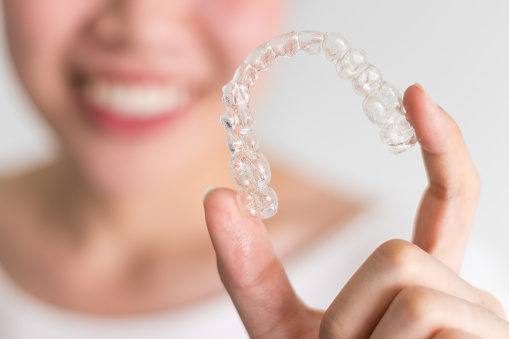 A girl holding her Invisalign Aligner