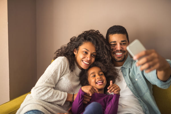 Family sitting on a couch and smiling for a selfie after dentist appointment