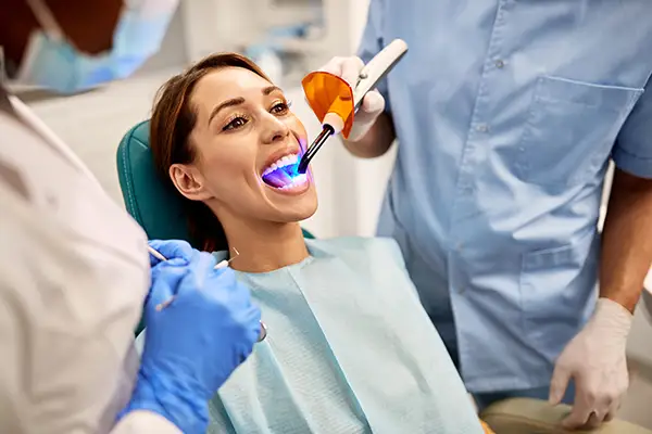 Dentist and assistant performing a dental bonding procedure on a female patient San Francisco, CA