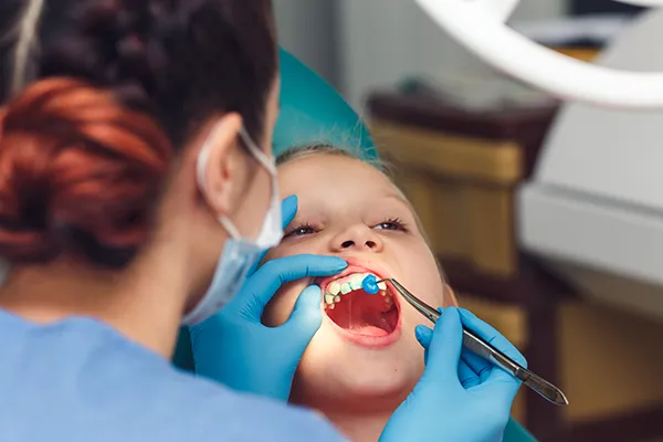 Young boy patiently keeping his mouth open while dental assistant applies fluoride Young boy patiently keeping his mouth open while dental assistant applies fluoride