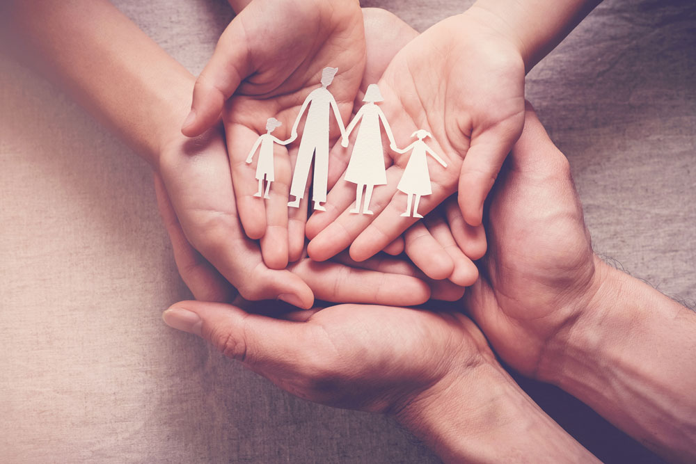 Hands extended holding a family of paper dolls in San Francisco, CA