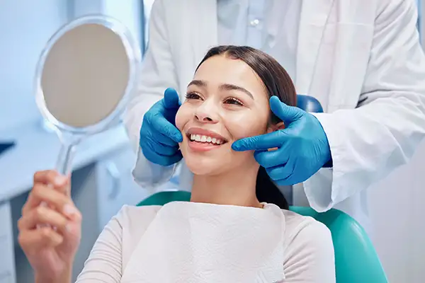 Smiling dental patient looking into mirror after a cleaning at San Francisco Dental Arts in San Francisco, CA