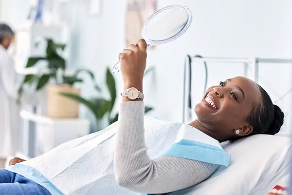 Smiling dental patient looking into mirror after wisdom teeth removal at San Francisco Dental Arts in San Francisco, CA