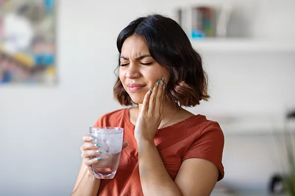 Young woman rubbing her jaw and wincing in pain with TMJ issues in San Francisco, CA