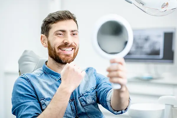 Bearded patient checking out his handsome smile in a mirror while sitting in a dental chair at San Francisco Dental Arts in San Francisco, CA