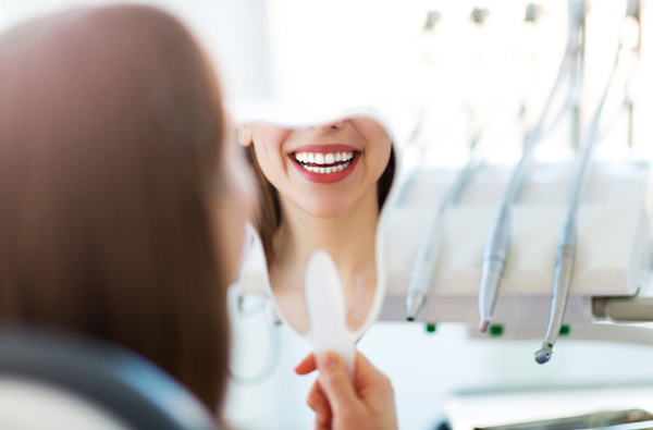 Woman looking at her smile in a mirror at San Francisco Dental Arts in San Francisco, CA