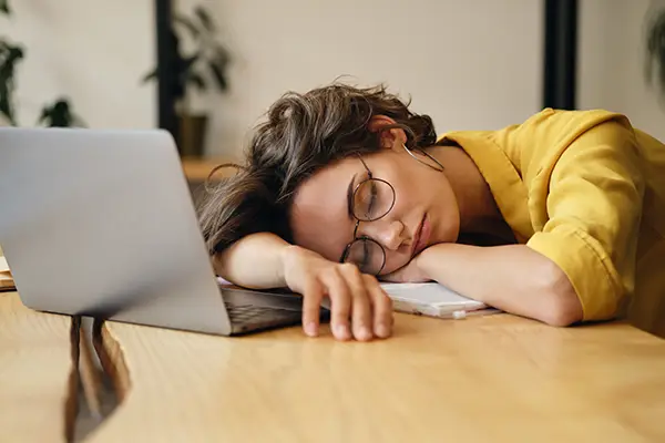 Tired woman sleeping on her laptop and needing oral health tips from San Francisco Dental Arts in San Francisco, CA