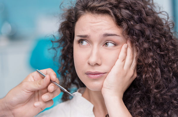 Woman holding cheek due to tooth ache at San Francisco Dental Arts in San Francisco, CA